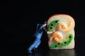 Miniature figurine of a man pushing a giant sandwich on a black background Royalty Free Stock Photo