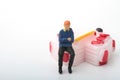 Miniature figurine of a man sitting on a giant cake Royalty Free Stock Photo
