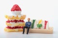 Miniature figurine of a man sitting on a giant sandwich and cake Royalty Free Stock Photo