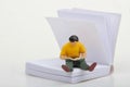 miniature figurine of a man sitting inside a giant book and reading