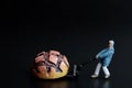 Miniature figurine of a man transporting a giant loaf of bread with a cart
