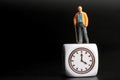 Miniature figurine of an old man with the icon of a watch on a black background Royalty Free Stock Photo
