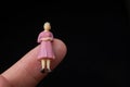 Miniature figurines of a woman sitting in the finger of a hand