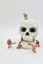 miniature figurines of workers with a huge human skull