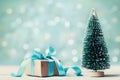 Miniature fir tree and christmas gift box against blue bokeh background. Holiday greeting card. Royalty Free Stock Photo