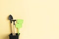 Miniature gardening tools and inscription board in flowerpot on beige background