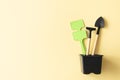 Miniature gardening tools and inscription board in flowerpot on beige background