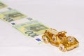 A miniature gold car drives along a road lined with euro bills. Euro bills worth 100 euros in blurred focus Royalty Free Stock Photo