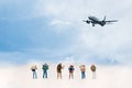 Miniature Group hiker and traveler with backpack standing and walking to airplane blue sky background,