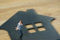 Miniature happy family figure standing on paper house as property or financial investment mortgage plan concept