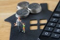 Miniature happy family figure standing on paper house with calculator as mortgage or financial investment plan concept