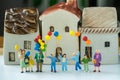 Miniature happy family holding balloons with ceramic house as pr