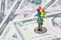 Miniature happy man holding colorful balloons on US Federal Reserve emblem on US dollars banknote as FED consider interest rate