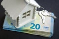 Miniature house, a bundle of money and keys are on a black surface Royalty Free Stock Photo