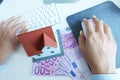 Miniature house on 500 cash euro banknotes in front of a businesswoman working on a computer Royalty Free Stock Photo