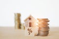 Miniature house on decrease percent icon on wood cube and stack of coins on wooden desk , for decreasing interest, lower price