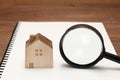 Miniature house, magnifying glass on blank notebook. Royalty Free Stock Photo