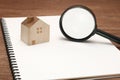 Miniature house, magnifying glass on blank notebook. Royalty Free Stock Photo