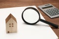 Miniature house, magnifying glass, calculator on blank notebook. Royalty Free Stock Photo