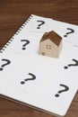Miniature house and many question marks on white papers. House with question marks. Royalty Free Stock Photo