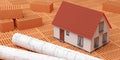 Miniature house model and architectural building construction drawing plans on stacked red bricks background, construction or Royalty Free Stock Photo
