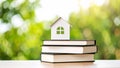 Miniature house model atop stack of books with blurred green background Royalty Free Stock Photo