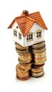 Miniature house perched on stacks of coins symbolizing home finance, AI-generated. Royalty Free Stock Photo