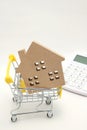 Miniature house, shopping cart and calculator on white background. Concept of buying new house, real estate and home mortgage. Royalty Free Stock Photo