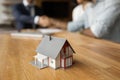 Miniature house on table, happy clients and realtor on background Royalty Free Stock Photo