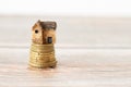 Miniature house on top of a stack of golden coins on a wooden background with copy space Royalty Free Stock Photo