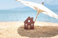 Miniature house and umbrella on beach, blue sea, sky on background. Real estate, property investment concept. Copy space Royalty Free Stock Photo