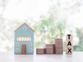 Miniature house, wooden blocks with the word TAX and stack of coins. The concept of paying tax for house and property Royalty Free Stock Photo