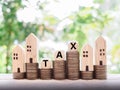 Miniature house, wooden blocks with the word TAX and stack of coins. The concept of paying tax for house and property Royalty Free Stock Photo