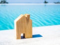 Miniature house wooden mock up over blurred pool on day. Image for property real estate investment concept Royalty Free Stock Photo
