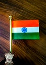 Miniature Indian National Flag on a metal stand on wooden table background.