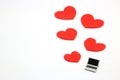 Miniature laptop and some red hearts on white background.