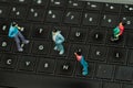 Miniature little people, group of friends over a computer keyboard, in a blurred background top view Royalty Free Stock Photo