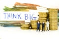 Miniature man: businessman with blurred word THINK BIG and many money. Image use for business, commitment, agreement, investment
