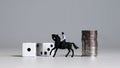 Miniature man riding a horse. Dice and coin stacks. Concepts about the probability of winning a race.