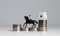 Miniature man riding a horse with a white dice on coin stacks.