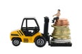 Miniature man sitting on a pile of Euro coins on a forklift truck