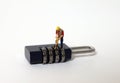 A miniature man standing on a locked combination lock.