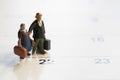 Miniature model family people, travelers standing on the calendar, traveling and planning concept