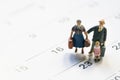 Miniature model family people, travelers standing on the calendar, traveling and planning concept