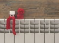 Miniature model house with knitted cap and scarf on heating radiator. Space for text. Saving heating in winter Royalty Free Stock Photo