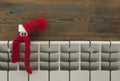 Miniature model house with knitted cap and scarf on heating radiator. Space for text. Saving heating in winter Royalty Free Stock Photo