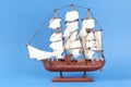 Miniature model of old ship with white sails on blue background Royalty Free Stock Photo