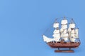 Miniature model of old ship with white sails on blue background, space for text Royalty Free Stock Photo