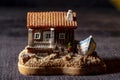 miniature model of a small house with a boat beside it, under a dark night background. Royalty Free Stock Photo