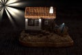 miniature model of a small house with a boat beside it, under a dark night background. Royalty Free Stock Photo